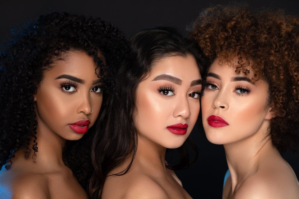 Close-up portrait of diverse women with striking red lips, emphasizing beauty and confidence.